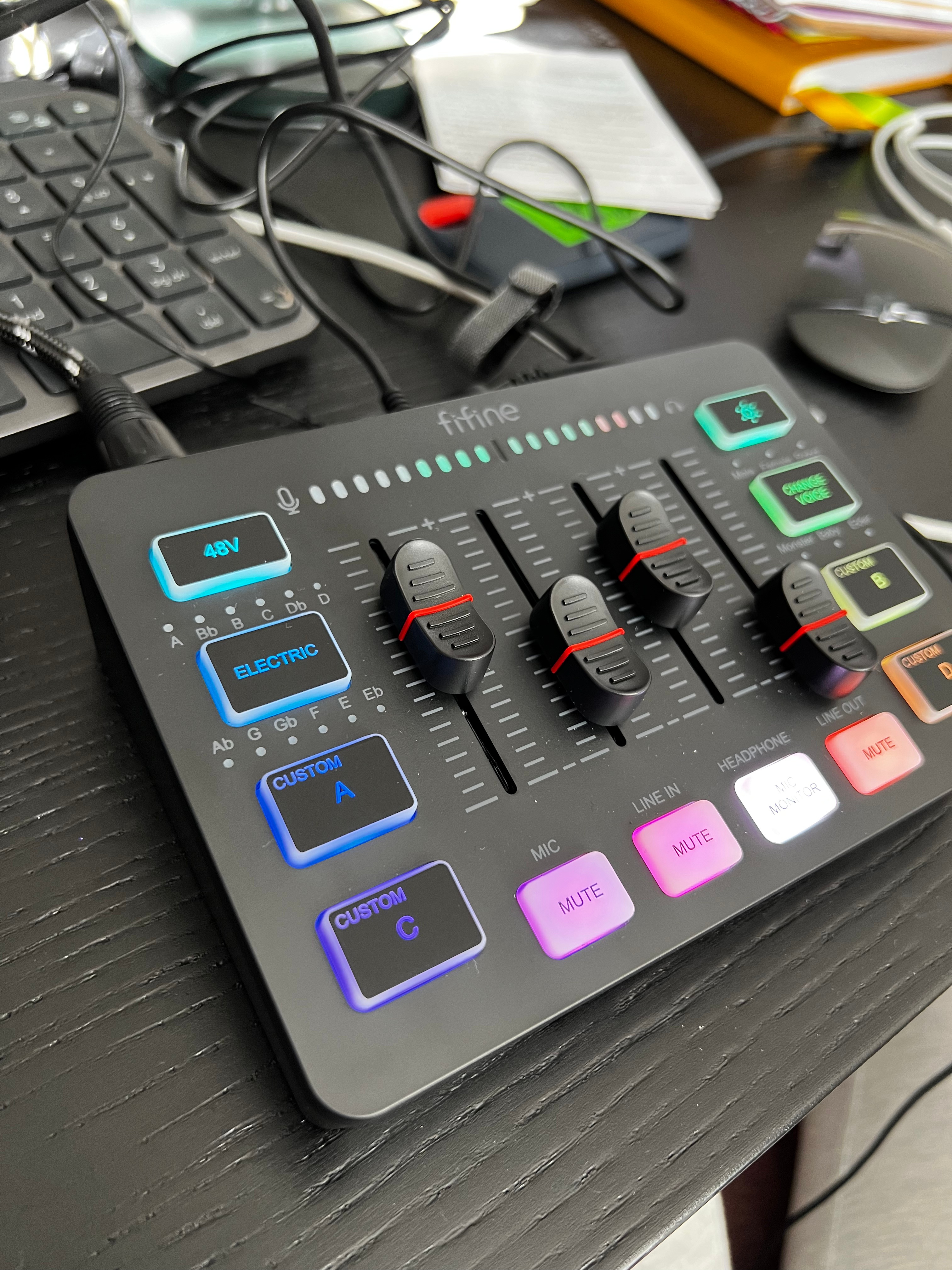 FIFINE brand gaming audio mixer sitting on cluttered desk